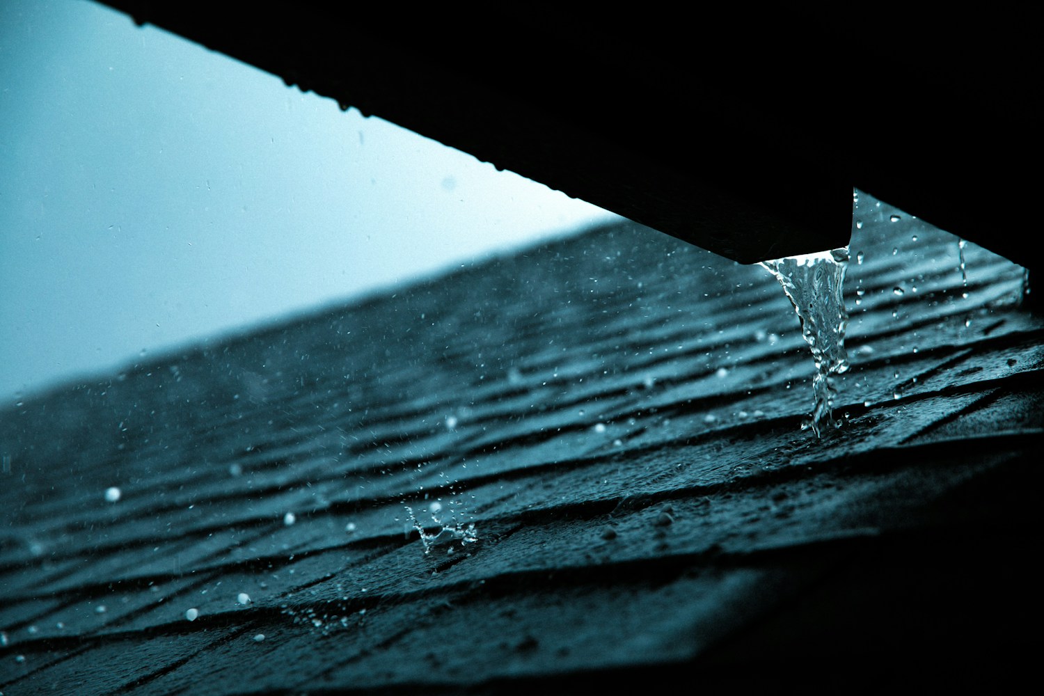 Rainwater flowing from a gutter outlet onto a wet roof